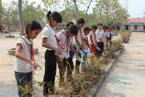Học sinh Trường Tiểu học Ea H’leo mang nước từ nhà đến tưới bồn hoa, cây cảnh của trường.
