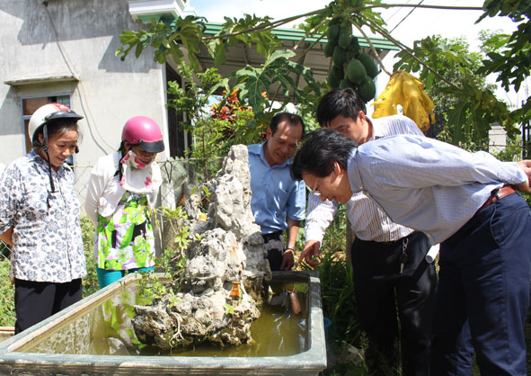Ông Doãn Hữu Long (người ngoài cùng bên phải) kiểm tra chỉ số lăng quăng trong các dụng cụ chứa nước tại các hộ dân ở tổ dân phố 9, thị trấn M’Đrắk (huyện M’Đrắk).  Ảnh: K.O