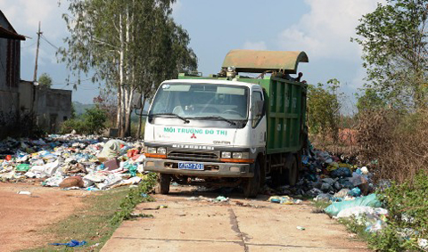 Xe rác của Công ty Hoàng Phương Nam đang đổ rác trên đường.  