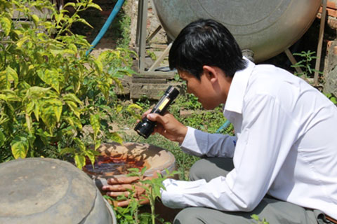 Cán bộ Trung tâm Y tế huyện M'Đrắk kiểm tra lăng quăng trong dụng cụ chứa nước của các hộ dân trên địa bàn. 