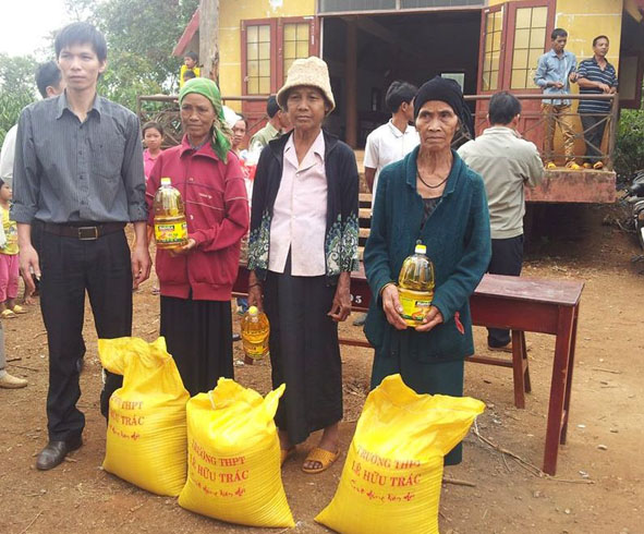  Ông Nguyễn Tự Do, Phó Hiệu trưởng Trường THPT Lê Hữu Trác (bìa trái)  trao quà tặng các hộ nghèo buôn Cuôr trong dịp Tết Giáp Ngọ 2014.