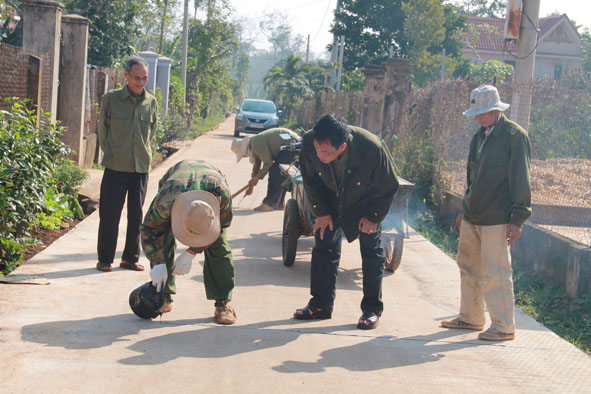 Người dân đang trám nhựa đường vào khe co giãn của con đường bê-tông mới được hoàn thành ở thôn 15, xã Hòa Đông, huyện Krông Pak.
