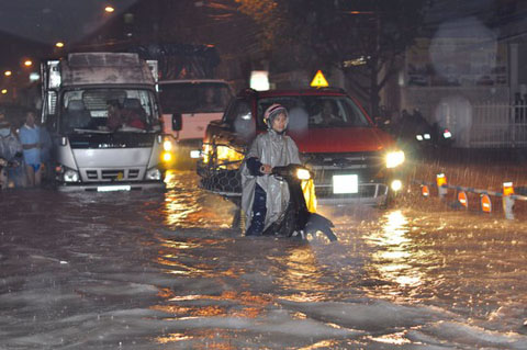 Người dân vất vả lưu thông trong trời mưa, đường bị ngập sâu ở TP Biên Hòa, tỉnh Đồng Nai Ảnh: XUÂN HOÀNG