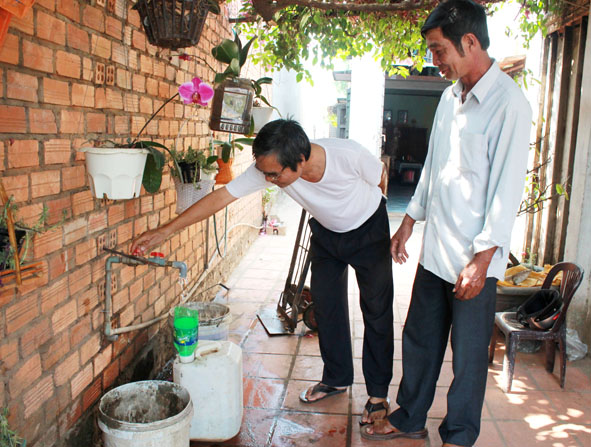 Ông Lê Văn Tư (bên phải), Hội trưởng Hội dùng nước thôn 7 (xã Hòa Phú) kiểm tra việc cấp nước cho người dân trên địa bàn.