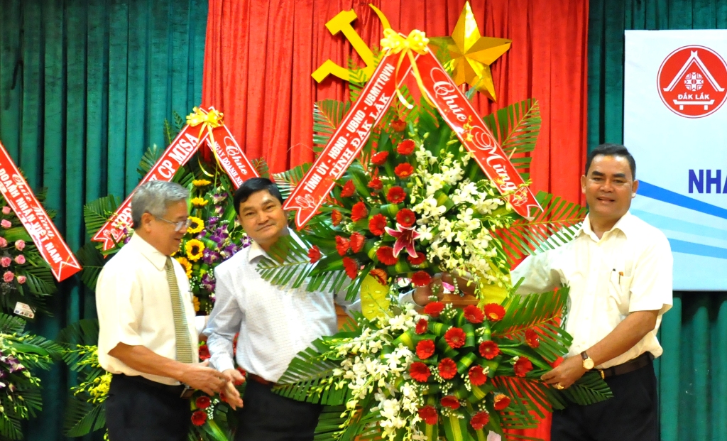 Chủ tịch HĐND tỉnh Y Biêr Niê (bìa phải) trao lẵng hoa chúc mừng của Tỉnh ủy, HĐND, UBND, UBMTTQ Việt Nam tỉnh tặng cộng đồng doanh nghiệp