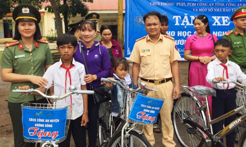 Đại diện phòng PV27, PC64 (Công an tỉnh) và cán bộ Công an huyện Krông Bông trao xe đạp cho các em.
