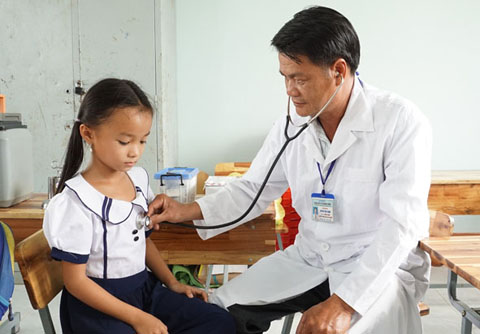 Bác sĩ Huỳnh Tấn Hạnh khám sáng lọc cho trẻ em tại xã Cư Pui trong chiến dịch  tiêm phòng viêm não Nhật Bản. 