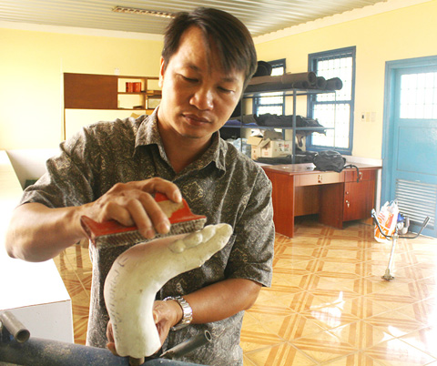 Anh Huỳnh Thanh Phong đang điều chỉnh một số chi tiết trên mô hình bàn chân được đúc bằng thách cao cho đúng với bàn chân thật của bệnh nhân phong.