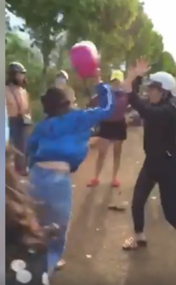 Nữ sinh mặc áo khoác xanh phang mũ bảo hiểm về phía đối phương. Ảnh cắt từ clip